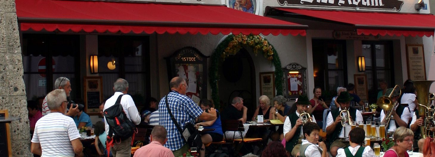 Biergarten vor dem Gasthaus zum Bier-Adam mit roten Markisen und Blasmusik