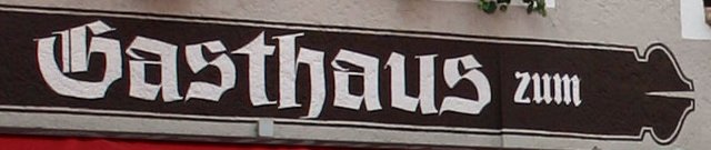 Das hölzerne Fraktur-Schild „Gasthaus zum“ an der Fassade